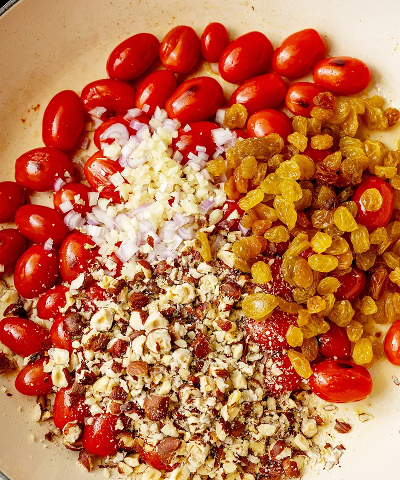 Add hazelnuts golden raisins garlic and shallot to tomatoes