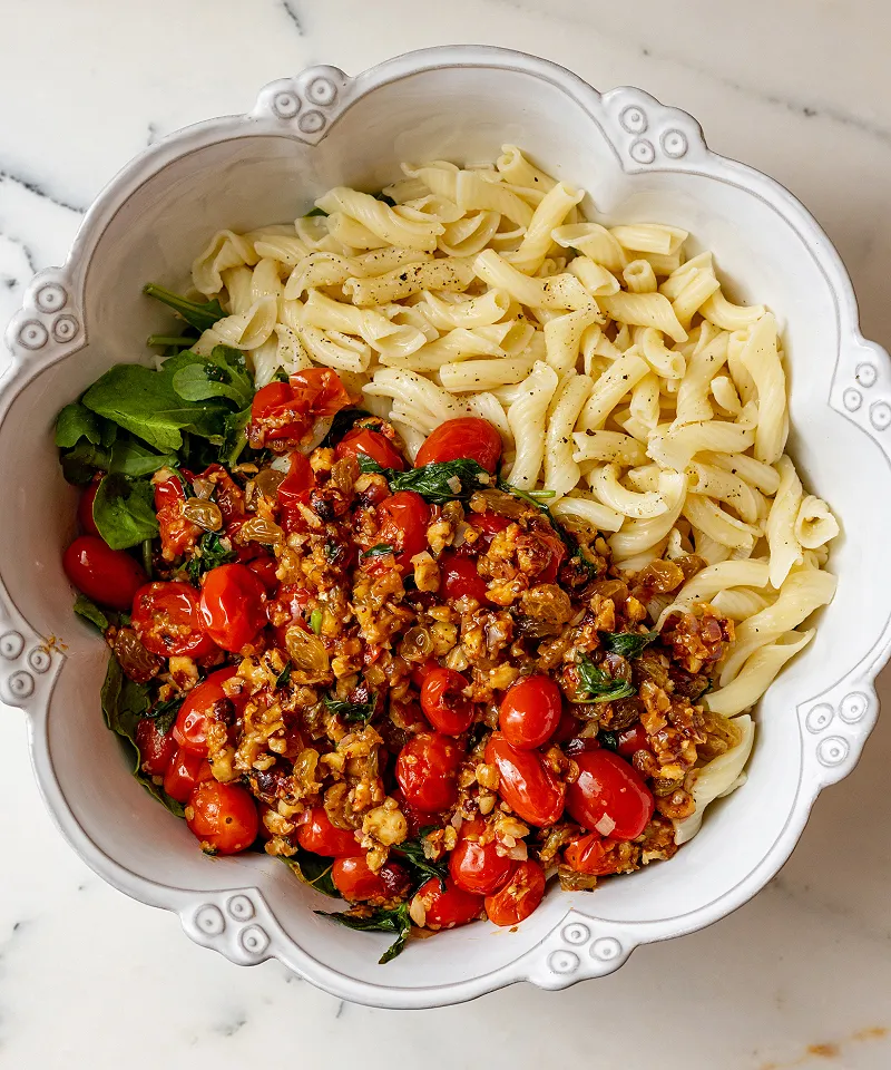 Add tomatoes to arugula pasta salad