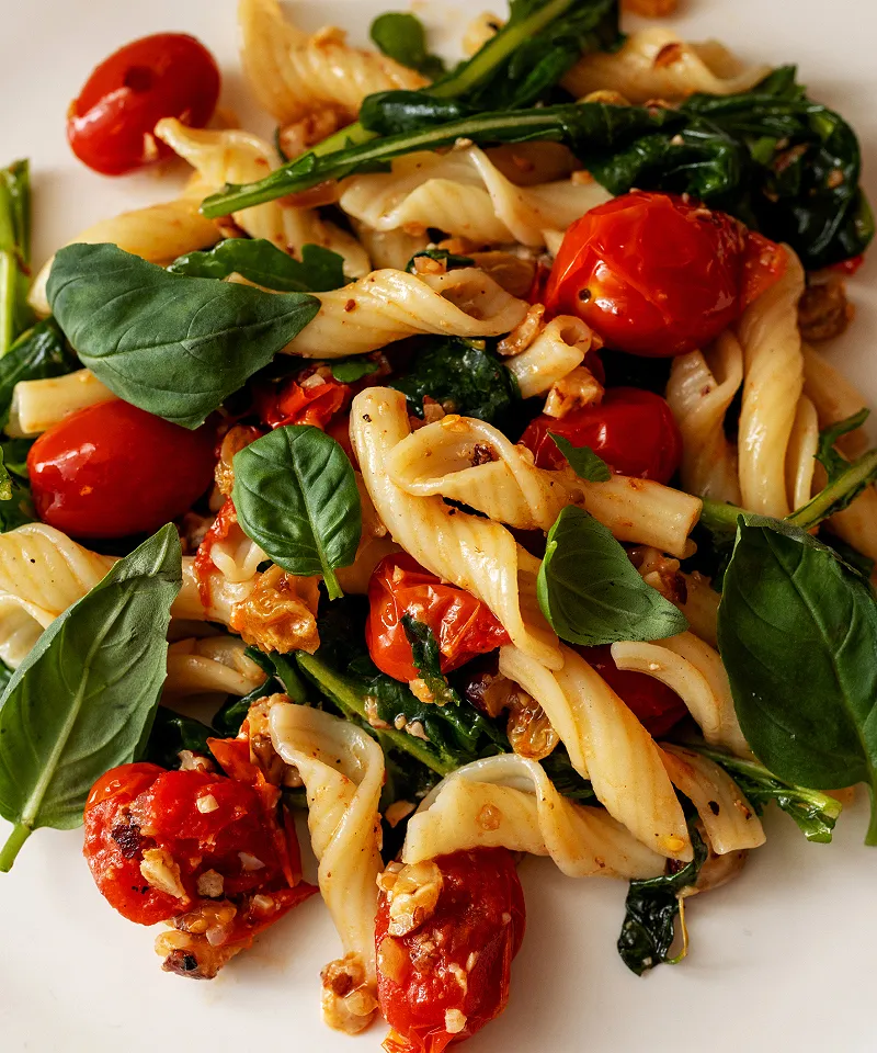Pasta salad with arugula tomatoes hazelnuts golden raisins